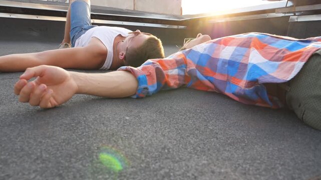 View on two young gays lying on roof with bright sunlight at background. Men resting and enjoying life together. Friends relaxing outdoor. Slow motion Close up