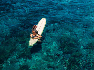 Woman on surfboard in blue sea. Aerial view of woman during surfing
