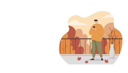 Relaxed man texting on a balcony during fall surrounded by orange leaves and nature