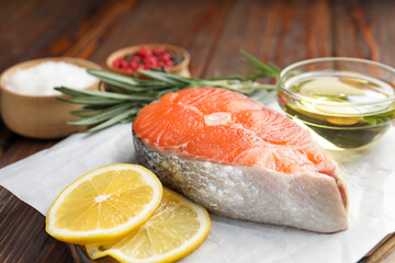 Piece of salmon fillet with spices, lemon and oil on table, closeup