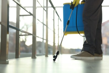 Fototapeta premium Pest control worker spraying insecticide indoors, closeup. Space for text
