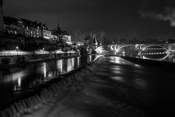 railroad bridge of Bremgarten is reflecting in the reuss river, monochrome long exposure picture