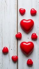Red glossy hearts arranged in love symbol on light wooden background