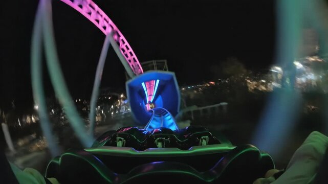 First-person POV of a thrilling roller coaster ride at night. Illuminated track with colorful LED lights and high-speed tunnel journey. Amusement park experience.