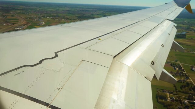 Jet extending flaps on wing, preparing for landing. Aircraft deploying trailing edge surfaces, getting ready to touch down. Plane adjusting wing configuration, setting up for descent to runway