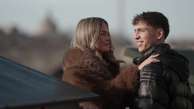 A young couple in Paris France The woman wearing a fur coat reaches out to embrace her boyfriend The city skyline is visible in the background conveying a sense of love and affection in a romantic set
