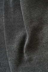 Dark gray upholstery fabric texture with soft folds and subtle light highlights