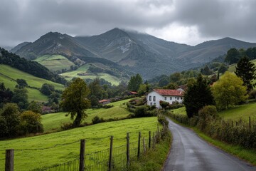 Obraz premium Scenic countryside view of a village with a road winding through lush green hills toward mountains