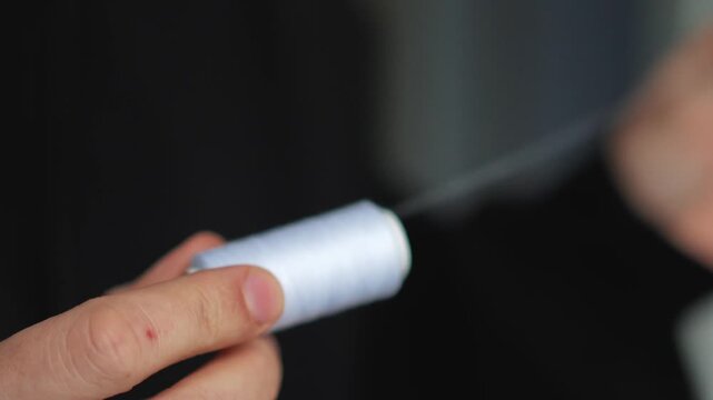 A skein of white sewing thread in a person's hands.
White thread for mending clothes and sewing holes.
Niktei, atelier, repair, clothing, skein, white