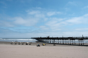 Pimentel beach in peru featuring a long pier and people enjoying the sandy shoreline and ocean under a blue sky