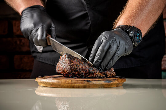Chef slicing roasted beef steak on board