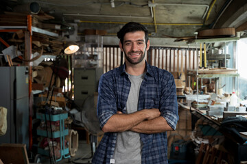Smiling luthier standing in workshop, confident craftsman in woodworking studio portrait