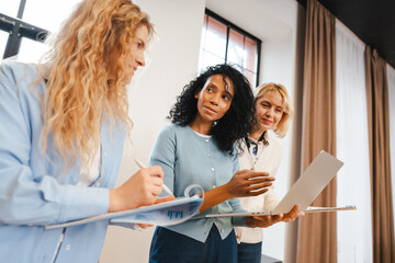 Diverse group of multinational women collaborating on business project in modern office