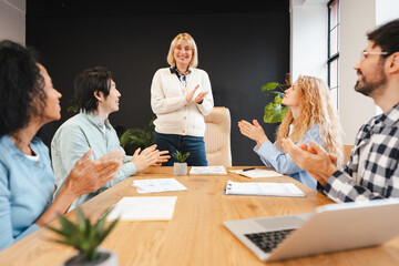 Smiling business team applauding presentation success in modern office