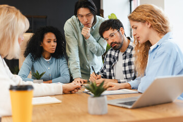 Diverse group of serious business team collaborating during productive office meeting