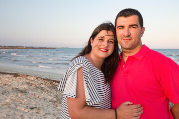 A middle-aged couple, looking happy, near the beach.