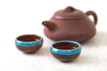 teapot and cups of black tea on a white wooden background