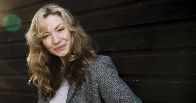 Attractive happy middle aged woman in her forties outside smiling and laughing in golden winter sunshine