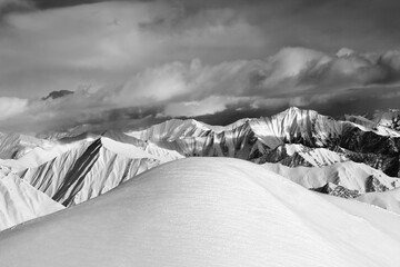 Black and white  off-piste snowy slope and cloudy mountains