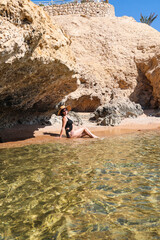 A woman swims on secluded wild beach among the rocks.
