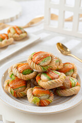 Delicious colorful cookies on a white plate with a gold spoon, perfect for dessert or baking photography