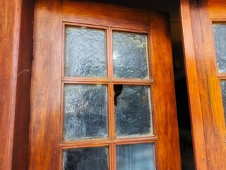 Fototapeta premium Old wooden window with cracked glass, rustic architecture detail showing age, decay, and vintage character