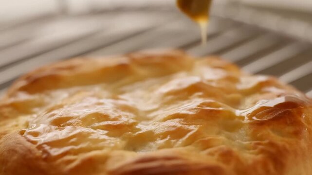 Golden pastry brushed with butter on cooling rack in crisp culinary closeup