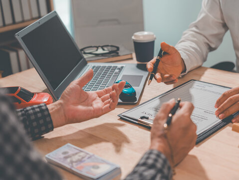 The car dealership calculates the interest rates and costs of a car loan, along with the terms and conditions of the contract, at their office. (Image close-up)