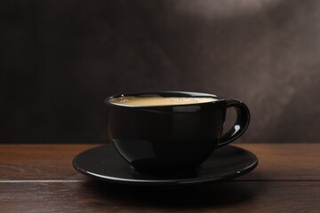 Aromatic coffee in cup on wooden table, closeup