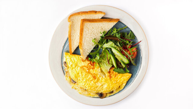 Top view of golden mushroom omelette served with toasted bread and fresh garden salad on a plate