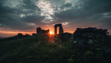 Obraz premium Ancient stone ruins at sunset with dramatic clouds and warm light