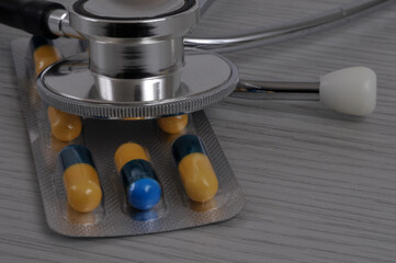 Blister de g&eacute;lules jaunes et bleues avec un st&eacute;thoscope en gros plan