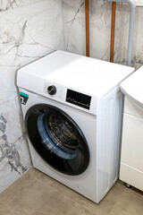 Modern laundry washing machine inside small bathroom interior