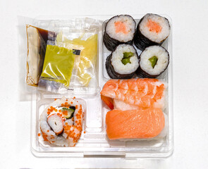 Japanese sushi rolls with wasabi and ginger inside plastic box