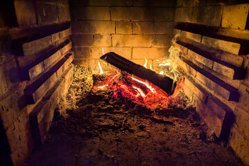 Wood is burning in a rural stove. Traditional stove in the countryside. Close-up of the hearth. Photo taken with a long exposure. Vertical photo
