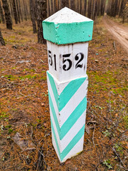 Marker post column of boundary forest quarter. District signpost for trees territory. Sign trail forester or tourists, so as not to get lost in site logging numbers and diagonal lines striped paint