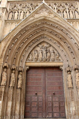 Obraz premium Entrance gate of Valencia Cathedral featuring historic Gothic stone architecture and religious details, taken in July 2024.