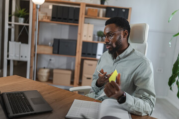 African American man in a video conference from a home office, presenting and explaining business reports during an online meeting, analyzing documents and discussing results with clients