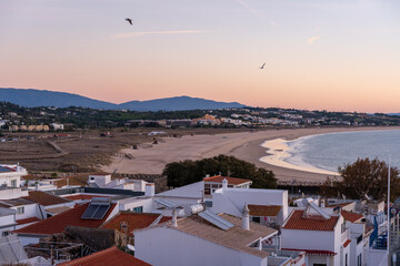 Praia de Sao Roque beach visible from Lagos city downtown, Portugal Algarve during sunrise with mountains visible in the background