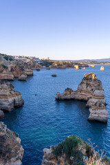 Cliffs and rocks near Praia do Camilo with mountains in the background during sunset in Algvare region of Portugal in Lagos