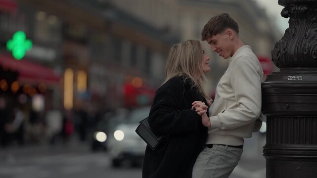 A young couple is holding hands in Paris France The lovers are in an intimate moment on a city street leaning against a lamp post Shallow depth of field.