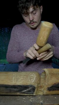 Artisan carving wooden totem with mallet and chisel
