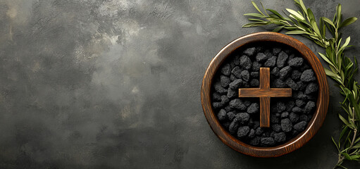 black ashes in a wooden bowl and an olive branch with a christian cross on a grey background