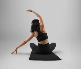 Mockup of black top, leggings on yoga trainer, sitting in asana on floor mat, rear view, isolated on background.