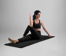 Template of black top, leggings on dark-haired woman yoga trainer, in asana on floor mat сloth, side view full height.