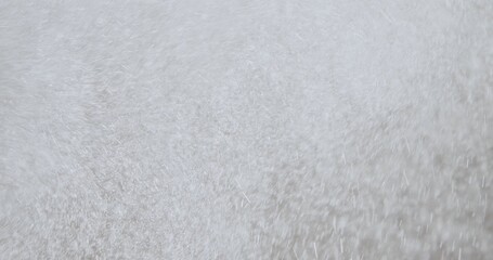 White particles or snowflakes falling diagonally on a soft purple background with a motion blur effect.