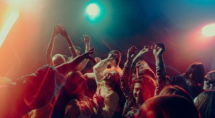 Expressive crowd movement during night music event. Concept of emotional intensity, shared experience, rhythmic freedom, immersive soundscape and Christmas party atmosphere.