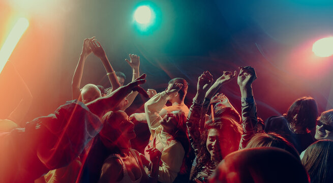 Expressive crowd movement during night music event. Concept of emotional intensity, shared experience, rhythmic freedom, immersive soundscape and Christmas party atmosphere. - Powered by Adobe