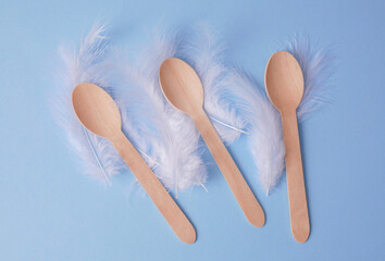 Wooden spoons with white feathers on blue background