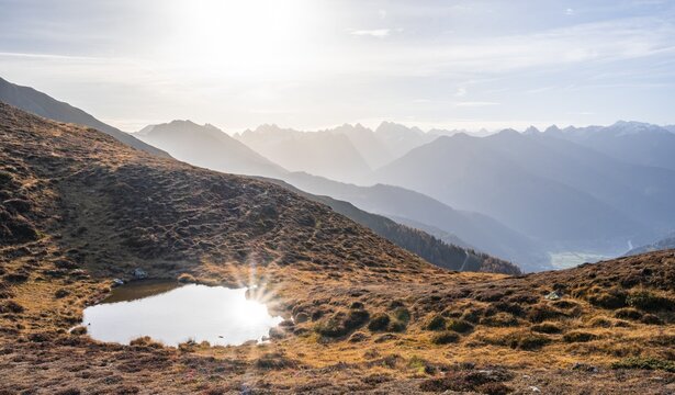 Small mountain lake on the Krahberg, sun star in the morning, mountain panorama in autumn, Venet crossing, &Ouml;tztal Alps, Tyrol, Austria